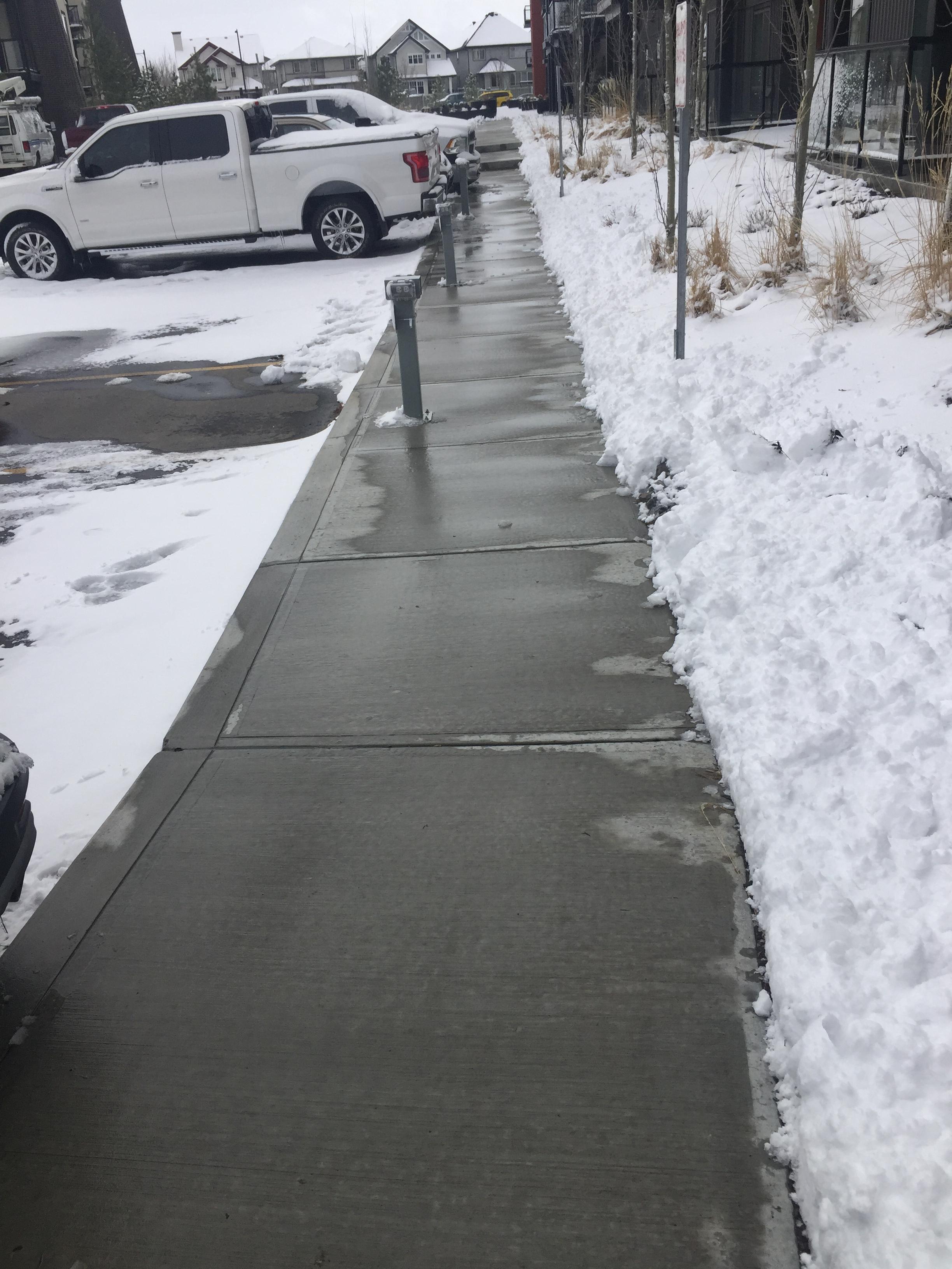 Commercial walkway alongside apartment buildings cleared with snow pushed to sides